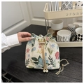 Dettaglio ricamo floreale su borsa a secchiello beige con coulisse di perle e catena - Verde