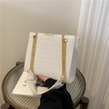 Sac blanc à motif crocodile avec bandoulière chaîne dorée sur un livre décoratif - Blanc