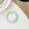 Detailed view of white circular phone grip with light green pearls on a white desk - Green