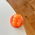 Nahaufnahme einer transluzenten orangefarbenen Bären-Handyhalterung auf weißem Tisch - Orange