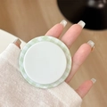 Close-up of a hand holding a green checkered magnetic phone grip for stable mobile support - Fruit Green