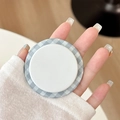 Macro view of a circular magnetic phone grip featuring a blue gingham pattern edge - Grey Green