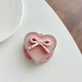 Dettaglio del supporto per telefono a cuore in pelle rosa con strass e fiocco su tavolo - GD Magnetico - Rosa