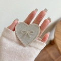 Close-up of heart-shaped phone grip with silver rhinestones and a crystal bow detail - Transparent Stand - Rhinestone Heart Bow - Star Diamond - Silver