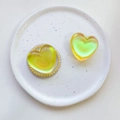 Detail of heart-shaped phone grip with iridescent pearl finish on ceramic display plate - Matte Heart-Iridescent Yellow