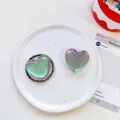 Macro shot of iridescent heart-shaped phone grips with pearl edge on ceramic tray - Matte Heart-Iridescent Grey
