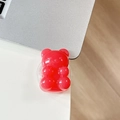 Close-up of a translucent red gummy bear phone grip on a silver laptop surface - Light Jelly Watermelon Red