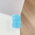 Detailed view of a translucent blue jelly bear phone grip stand on a white desktop surface - Light Jelly Blue