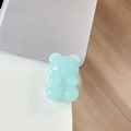Macro view of a light blue translucent jelly bear phone grip on a silver laptop surface - Light Jelly Light Green