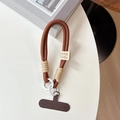 Macro view of thick brown braided phone wrist strap with coffee T-patch and clip - Brown