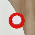 Close-up of red silicone protective corner guard installed on a white desk edge - Red