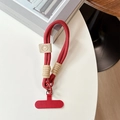 Close-up van rode gevlochten telefoonpolsband met lederen bedeltje op witte tafel - Smiley Gezicht Kort Touw + Rode Patch / Rood