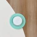 Detailed top view of mint green silicone corner protector with adhesive pad on wood surface - Dark Green