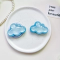 Detail view of cloud-shaped glitter phone grips in pearlescent blue on a ceramic plate - Pearlescent Cloud-Blue
