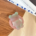 Dettaglio del supporto magnetico orso laser con sfumatura rosa e verde su tavolo di legno - Laser Marrone