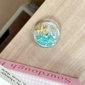 Macro view of ocean-style phone grip featuring sea stars and shells on a wooden background - Starry Sky Griptok Starfish Shell Stone / Lake Blue