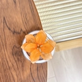 Gedetailleerde macro-opname van een oranje doorschijnend bloemaccessoire op een houten blad - Oranje