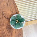 Détail de support téléphone fleur vert foncé avec pistil doré sur fond bois rustique - Vert