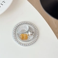 Dettaglio macro di un supporto per telefono in argento con strass e resina ambrata - Serie Argento N. 1(银系1号)