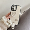 Detail of cream leather iPhone case with pearl heart embellishment and wrist strap - Pearlescent Hollow Heart Bow Pearl Chain / White / iPhone 16e