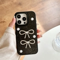 Detail of hand holding a black leather texture iPhone case with pearls and shiny bows - Large-hole Pearlescent Texture - Pearl And Rhinestone 2 Bows - Black / iPhone X/XS
