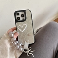 Detail of silver textured iPhone case featuring a pearl heart design and purple wrist strap - Pearlescent Hollow Heart Bow Pearl Chain / Silver / iPhone 16e