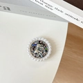 Detail of round phone grip with glitter base, silver bowtie and pearl rim on white desk - Glitter Black / Transparent Stand