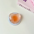 Detail shot of a translucent orange heart-shaped phone grip with a glossy glass-like finish - Magnetic-Crystal Glass Heart-Orange Dots