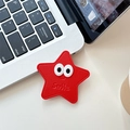 Détail du support téléphone étoile en cuir rouge avec yeux et logo Smile sur laptop - Style Yeux d'Étoile en Cuir / Rouge