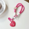 Close-up of pink braided phone lanyard with heart charm and leather smiley face accent - Rose Red