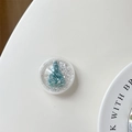 Macro shot of circular phone stand featuring a teal Christmas tree and silver glitter - Clear Quicksand Glitter Christmas Tree