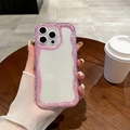 Custodia per iPhone con bordo ondulato glitter rosa tenuta in mano in un bar all'aperto - Bordo Luccicante Rosa / iPhone 16e