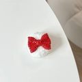 Macro detail of red rhinestone bow accessory with a soft white plush round base - Plush Rhinestone Bowknot Shape / Red
