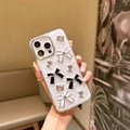 Dettaglio della cover iPhone con texture a conchiglia, fiocchi 3D e strass in mano - Fiocco Bianco e Nero / iPhone 7/8/SE 2020