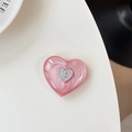 Dettaglio del supporto per telefono a cuore rosa perlato con logo argento lucido - Rosso Luccicante