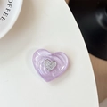 Detailed view of heart-shaped glitter phone grip with metallic logo on white surface - Purple Glitter