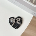 Close-up of heart-shaped portable makeup mirror with black base and silver glitter bow - Starry Silver Foil Bow #6 / Black
