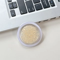 Detailed macro view of champagne gold glitter sequins in a round transparent container - Yellow