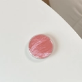 Detailed top view of pink solid cream blush in a round transparent minimal container - Red
