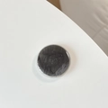Detail of round dark gray textured phone grip with a polished glossy finish on white surface - Gray