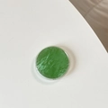 Close-up of green solid pigment inside a round transparent phone grip mount holder - Matcha Green