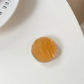 Detalle macro del soporte redondo de resina ámbar para móvil con copos de pan de oro - Naranja