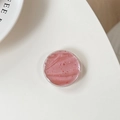Detail of round pink glitter phone grip with red sequins on a minimalist white surface - Red