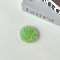 Detail shot of a round phone grip featuring green heart-shaped holographic sequins inside - Candy Heart / Green