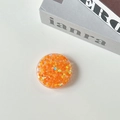 Dettaglio di un supporto rotondo per telefono con paillettes arancioni a forma di cuore - Cuore di caramella / Arancione