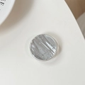 Vista macro de soporte circular para móvil con láminas plateadas y textura de mármol - Blanco