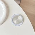 Macro shot of minimalist crystal glass magnetic phone grip base with white circular ring - Clear