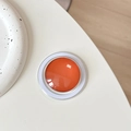 Close-up of orange magnetic phone grip with transparent dome on minimalist background - Dark Orange