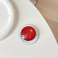 Close-up of a glossy red magnetic phone grip on a white desk with ceramic decor - Burgundy