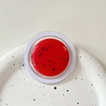 Macro view of a watermelon-style red glitter balm in a transparent circular MagSafe holder - Magnetic Morandi Ink Splash Bright Red